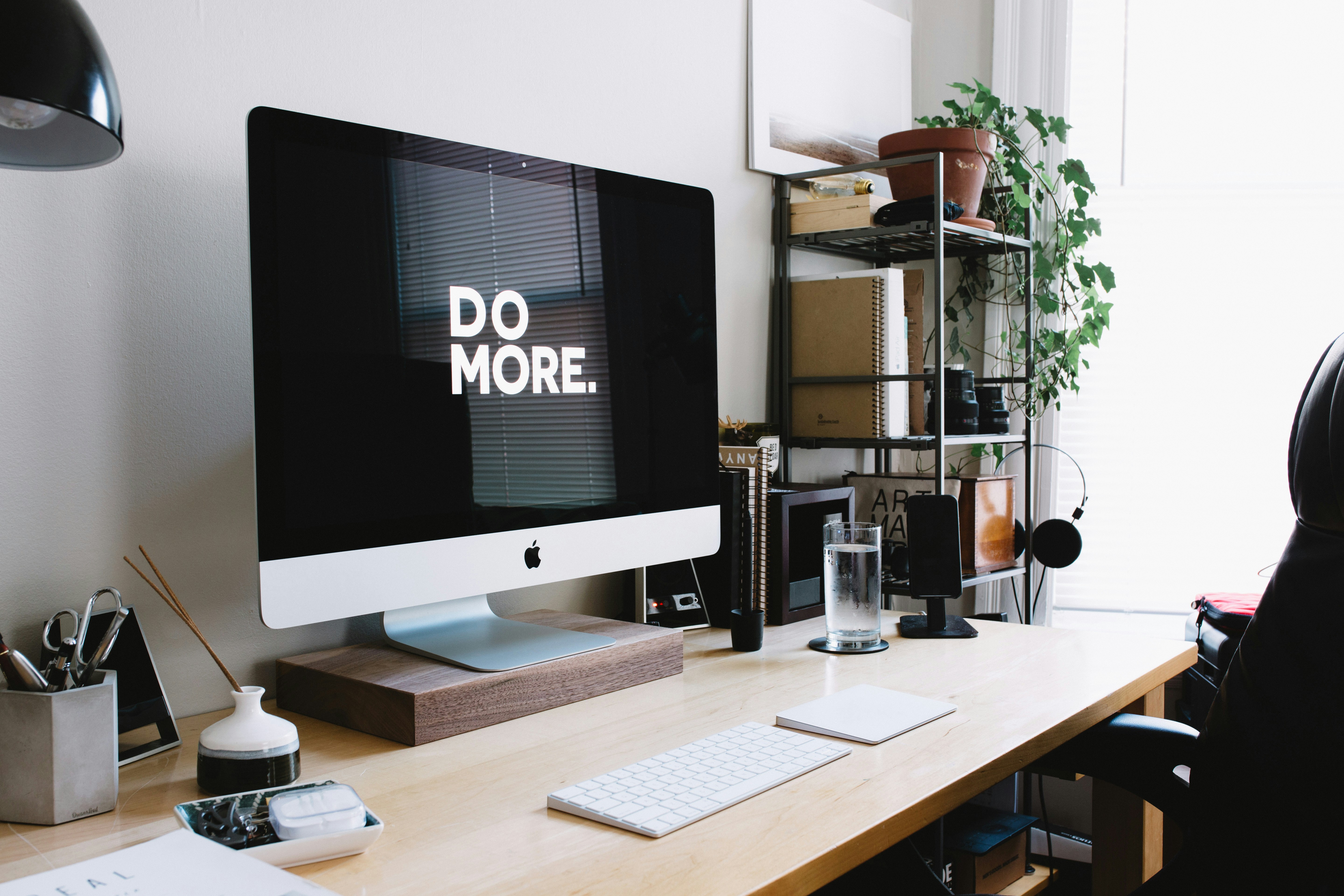 Et organisert skrivebordsoppsett med en iMac som viser teksten «DO MORE.» på skjermen.